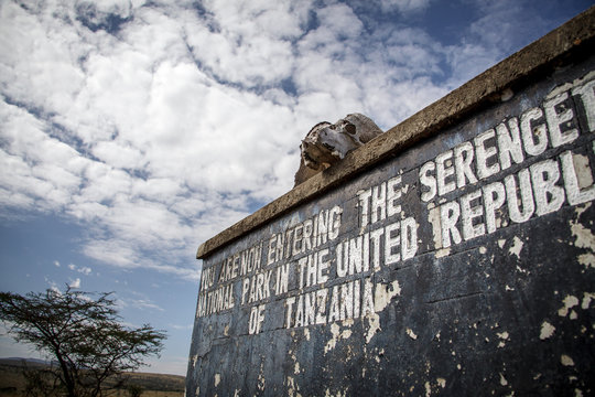 Worn sign on the Kenya - Tanzania border signaling the entrance to the Serengeti