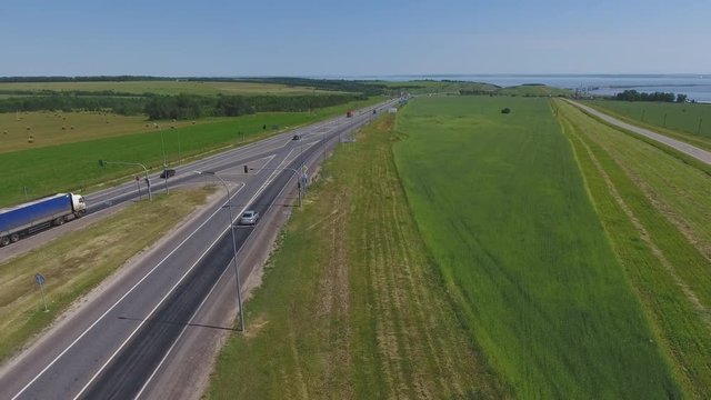 The intersection of highways. The movement of cars on the road. Top view of the intersection, cars, field and river. Summer video from the drone. Rural landscape.