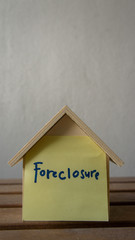 Fototapeta na wymiar House or home model with text foreclosure. Property or real estate concept.