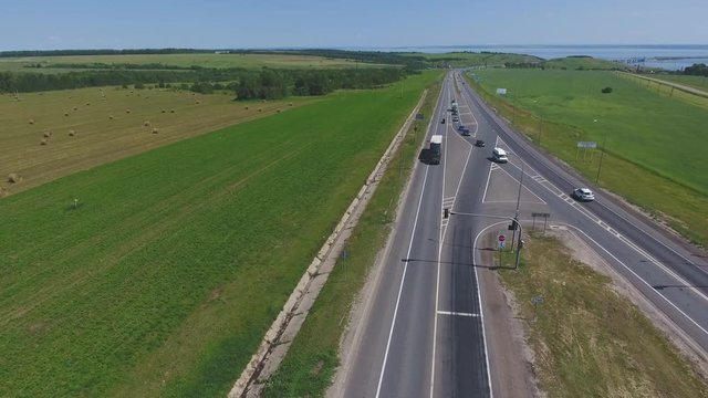 The intersection of highways. The movement of cars on the road. Top view of the intersection, cars, field and river. Summer video from the drone. Rural landscape.