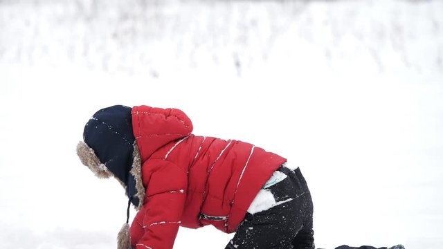 Happy little child with big fur cap play with snow, joy of winter
