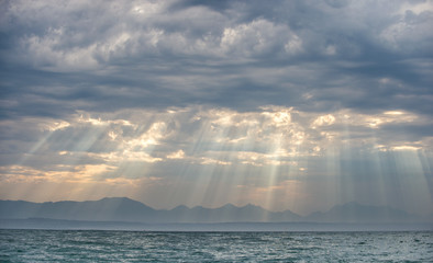 Seascape with clouds sky. The rays of the sun through the clouds in the dawn sky, Silhouettes of Mountains on the Horizon. False bay. South Africa. 