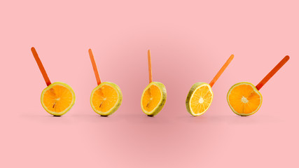 sliced orange fruit on a stick. pink background