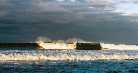 Powerful ocean wave breaks on a shallow bank. Stormy weather. Seascape.
