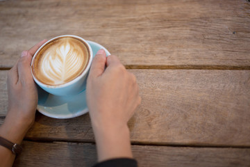 Hand Women put a Latte arts coffe hot coffee on wooden table.barista art concept.