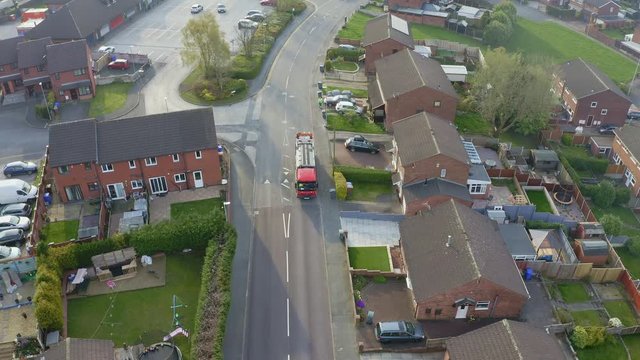 A bin lorry, refuse collection vehicle makes it way up the road as men load recycling bins into the waste compactor in a middle/working class area in the city
