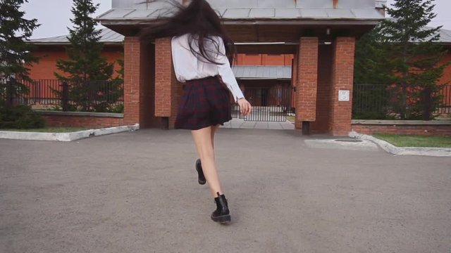 Attractive woman jumping to gates and turns around. Lady smiles nicely, happily. Female reaches the end of the brick arch and we can very well see her slim legs and short skirt while she is jumping.