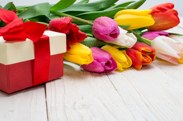 bouquet of tulips with a gift on rustic wooden board