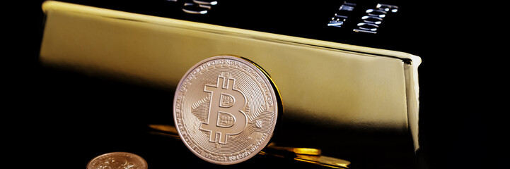 Bitcoin cryptocurrency and gold bar on a black background.