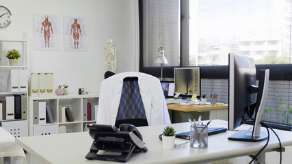 bright and modern medical doctor office complete with personal computer and telephone on desk white...