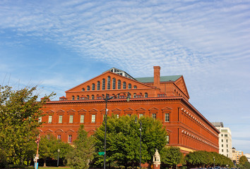 National Building Museum in Washington DC, USA. The building in early autumn with deciduous trees around its perimeter.