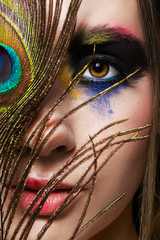 Female portrait with peacock feather on foreground and beauty face makeup.