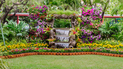 Waterfall flows and vivid flowers pot decoration in cozy home flower garden on summer.