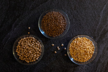chickpeas lentils and peas in transparent plates on a dark background