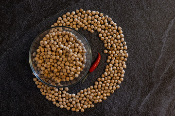 chickpeas in the form of a circle in a plate on a dark background with a hot pepper horizontal orientation