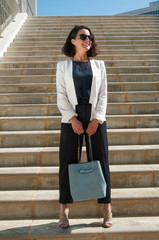 Long shot of businesswoman standing on stairs, looking confident