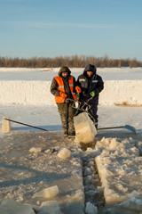 Obraz premium Installers with steel tongs pull out the ice block