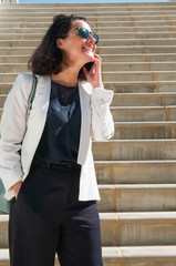 Smiling businesswoman standing on stairs, talking on phone
