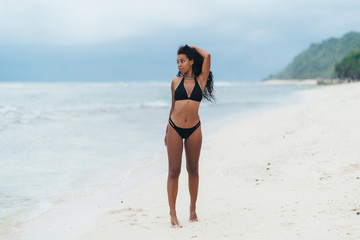 Sexy african american girl in swimwear resting on ocean beach, young black skinned woman