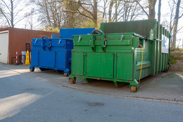 two garbage compactors are standing in the courtyard of a hospital