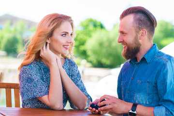 Marry me concept. Loving couple getting engaged in an outdoor cafe.