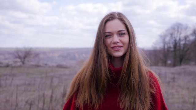 Portrait of happy beautiful brunette girl in a red sweater. Steady cam shot, slow motion.