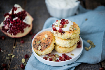 Cheesecakes for Breakfast decorated with pumpkin seeds and pomegranate seeds. Selective focus.