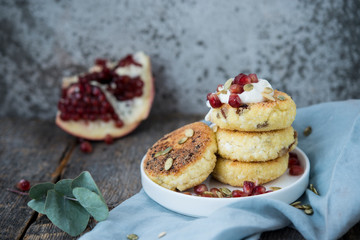 Cheesecakes for Breakfast decorated with pumpkin seeds and pomegranate seeds. Selective focus.