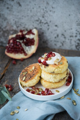Cheesecakes for Breakfast decorated with pumpkin seeds and pomegranate seeds. Selective focus.