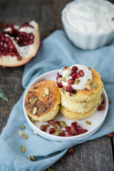 Cheesecakes for Breakfast decorated with pumpkin seeds and pomegranate seeds. Selective focus.