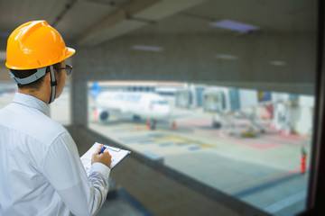 Male engineer inspection checking on blurred airport background With note on notepad or...