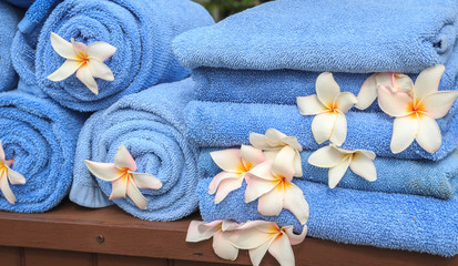 Obraz na płótnie Canvas Blue towels decorated with white plumeria flowers waiting for tourists at swimming pool in a luxury resort