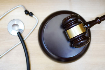 Judges gavel, sounding block and stethoscope on light wooden background, selective focus at sdf. Medical law system, health law, medical jurisprudence and justice concept.