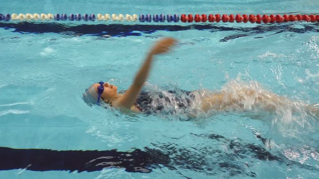 Training of female amateur swimmer doing backstroke in swimming pool, Full HD steadycam shot