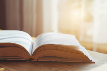 open book on wooden table, morning light