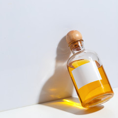 A glass bottle with a wooden cork filled with oil stands on a white table. The concept of body care. SPA