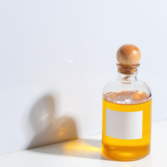 A glass bottle with a wooden cork filled with oil stands on a white table. The concept of body care. SPA