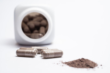 Herbal medicine in capsule isolate on white background. Herb black Galingale powder extract. Herbal medicine with open clear capsules. Alternative supplement for good healthy.