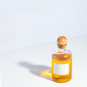 A glass bottle with a wooden cork filled with oil stands on a white table. The concept of body care. SPA