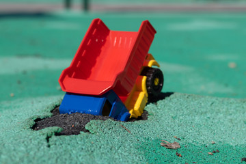 The car fell into the pit. Toy plastic truck with a red body had an accident. Hole on Asphalt Coating. Accident has occurred