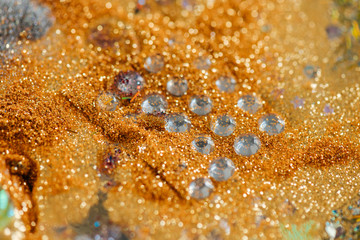 Paper with gluer transparent fake crystals being surrounded with golden glitter