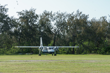 Ein kleines Flugzeug mit zwei Propeller steht auf einer Landebahn aus Graß