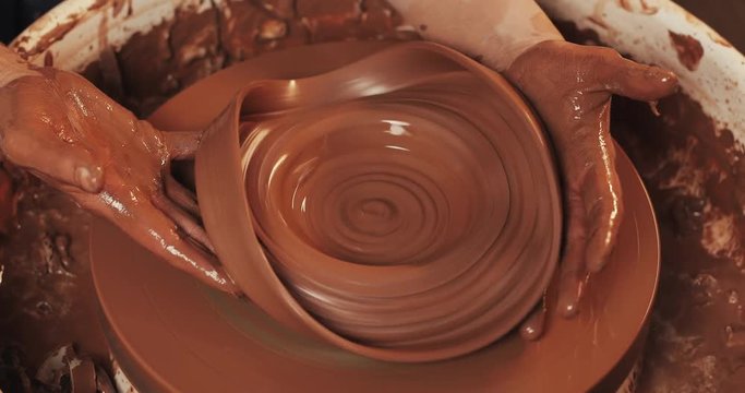 Hands of potter breaks clay jug on potter's wheel. Pottery training, close up.