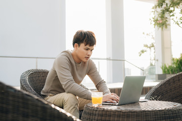 A young man using laptop computer while sitting on a sofa outside