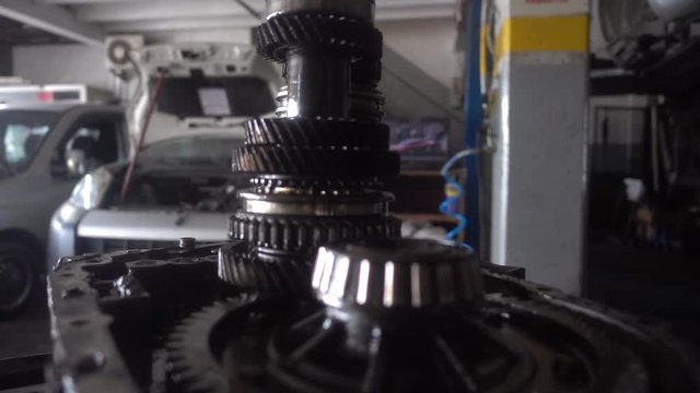 Clear and crisp slow-motion pan shot of a car in a car repair shop. The shot slowly zooms in on some gears, giving the scene an intense and interesting vibe.