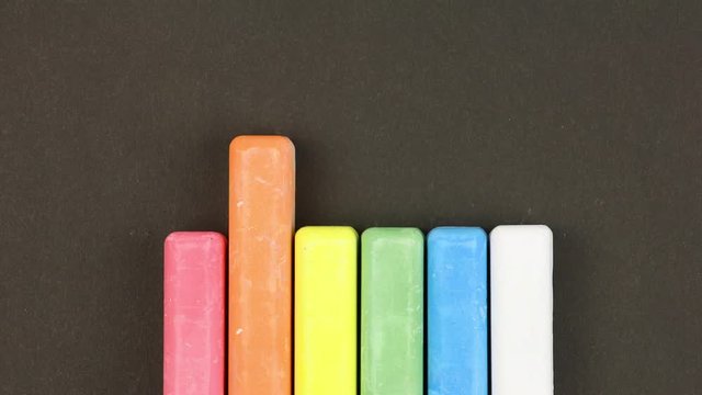 six colored children crayons on black background lined in a row, crayons come out  randomly, closeup, loop video, stopmotion animation, kindergarten education concept