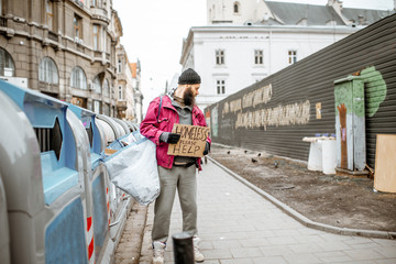 Portrait of depressed homeless beggar with cardboard begging some money on the street in the city