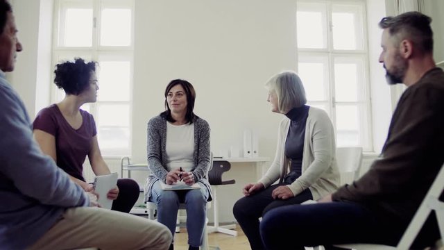 Men and women sitting in a circle during group therapy, talking.