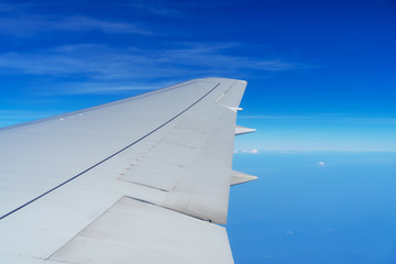 Obraz premium Wing of airplane flying in the sky on a clear day