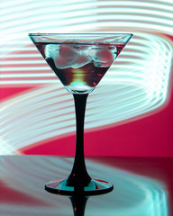 glass with cocktail and ice on a beautiful background with neon stains